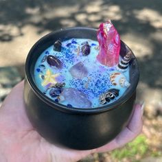 a hand holding a black bowl filled with blue liquid