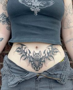 a woman's stomach with a bat tattoo on her lower body and the bottom part of her abdomen