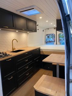 the interior of a camper with black cabinets and wood counter tops is seen through an opening in the kitchen