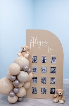 a teddy bear sitting on top of a bunch of balloons next to a photo frame