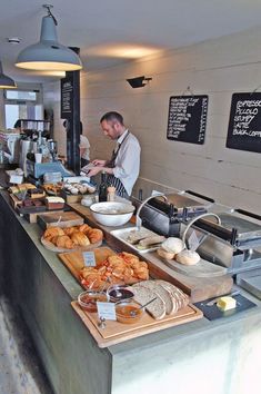 a man standing in front of a counter filled with breads and other food items