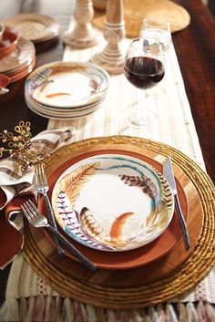 a table set with plates, silverware and wine glasses