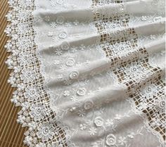 white lace with flowers on it sitting on top of a wooden table