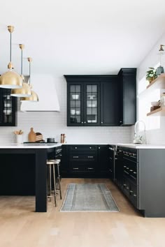 a kitchen with black cabinets and white counter tops is seen in this image, there are stools at the center of the room