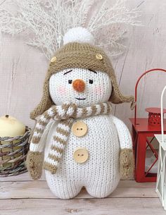 a knitted snowman sitting on top of a table next to a red lantern