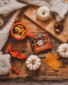 pumpkins, books and other autumn decorations on a wooden table with an open book