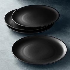 two black plates sitting next to each other on top of a gray tablecloth covered surface