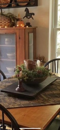 a wooden table topped with a plate filled with food next to a glass cabinet and window