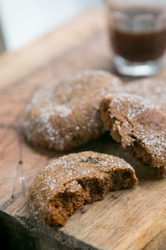 two cookies on a cutting board next to a glass of chocolate