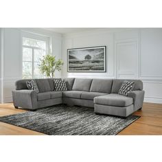 a living room with a gray sectional couch and black and white throw pillows on the rug