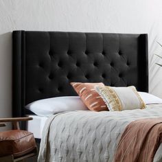 a black headboard with two pillows on top of it next to a brown chair