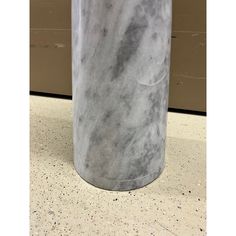 a large gray marble trash can sitting on top of a cement floor next to a door