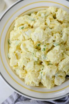 a bowl filled with potato salad on top of a white and yellow striped table cloth