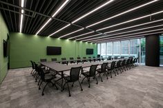 an empty conference room with green walls and black chairs on the floor, along with flat screen tvs