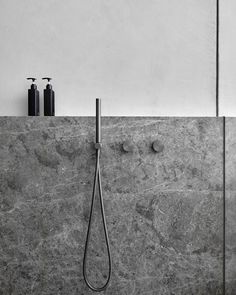 a black and white photo of a shower with two soap dispensers on the wall