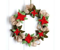 a christmas wreath hanging on a door with red and green poinsettia flowers