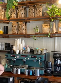 a woman standing in front of an espresso machine filled with lots of coffee