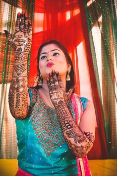 a woman holding up her hands with henna tattoos on it's arms and chest