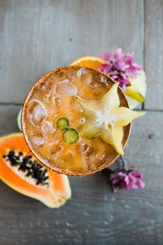 an overhead view of a drink in a glass with fruit on the table next to it