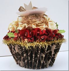 a cupcake decorated with red, white and gold decorations is shown in front of a white wall