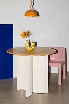 two chairs and a table with a vase on it in front of a blue wall