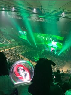 a large crowd at a sporting event with green lights on the stage and fans in the stands