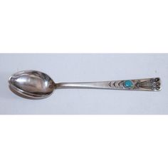 a silver spoon with a turquoise bead on it