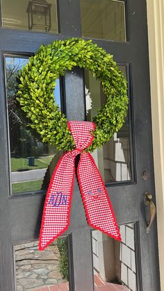 a red and white checkered bow hangs on the front door