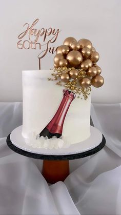 a white cake topped with gold balls and a wine bottle