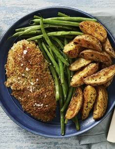 a blue plate topped with green beans and fried meat covered in seasoning next to potatoes