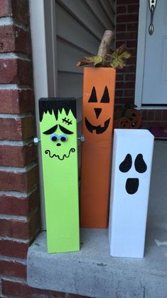 three halloween decorations are sitting on the front porch, one is painted orange and one is green