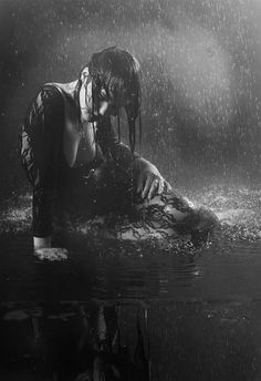 black and white photograph of a woman in the rain with her head down on an object