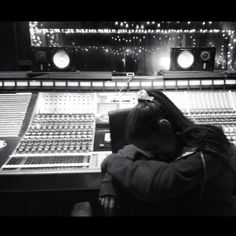 a woman sitting in front of a mixing desk with lights on the wall behind her