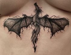 a woman's chest with a black dragon tattoo on the top and bottom part