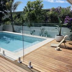 an empty swimming pool in the middle of a wooden decked area with glass railings