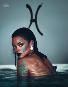 a woman with makeup on her face and body in the water next to a large pair of scissors