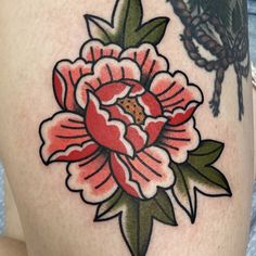 a woman's thigh with a flower tattoo design on the leg and an insect in the background