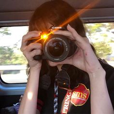 a woman taking a photo in the back seat of a car with her camera up to her face