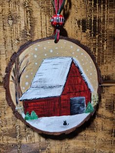 a red barn ornament hanging on a wooden wall