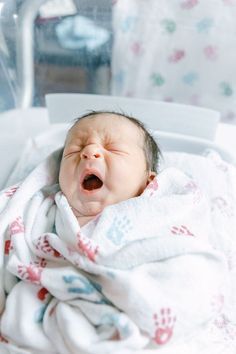 a baby is yawning while wrapped in a blanket