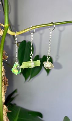 three necklaces hanging from a green plant