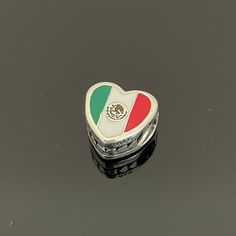 a small heart shaped box sitting on top of a black surface with the flag of italy painted on it