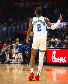 a basketball player is walking on the court with his hand in the air while people watch