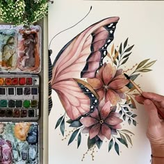 a woman is painting a butterfly with watercolors