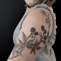 a woman's arm with flowers and leaves tattooed on the back of her shoulder