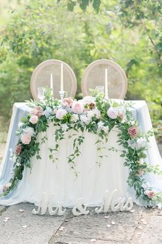 the table is set with flowers and candles for an elegant wedding reception in the woods