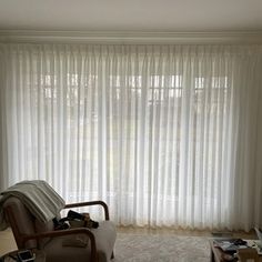 a living room with a couch, chair and television in front of a large window