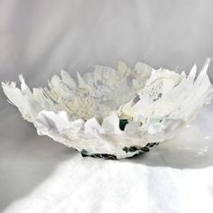 a white paper flower sitting on top of a white tablecloth covered floor next to a wall