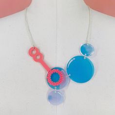 a necklace with two different colored buttons attached to it's sides, on a mannequin torso