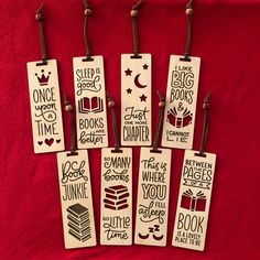 six bookmarks are hanging on a red cloth with some writing in the middle and other words below them